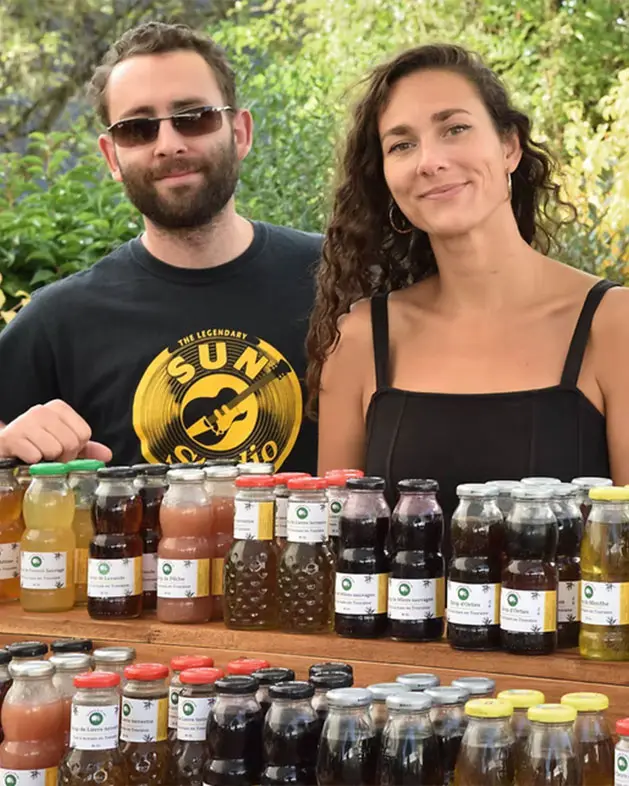 Photo de Rémi et Éléonore derrière un stand de produits artisanaux